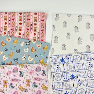 Könnte beinhalten: Eine Sammlung gemusterter Stoffe mit verschiedenen Designs. Enthält rosa Stoff mit Bären und Erdbeeren, blauen Stoff mit Hühnern und rosa Stoff mit Katzen. Weitere Stoffe haben Pinguin- und nautische Themen.