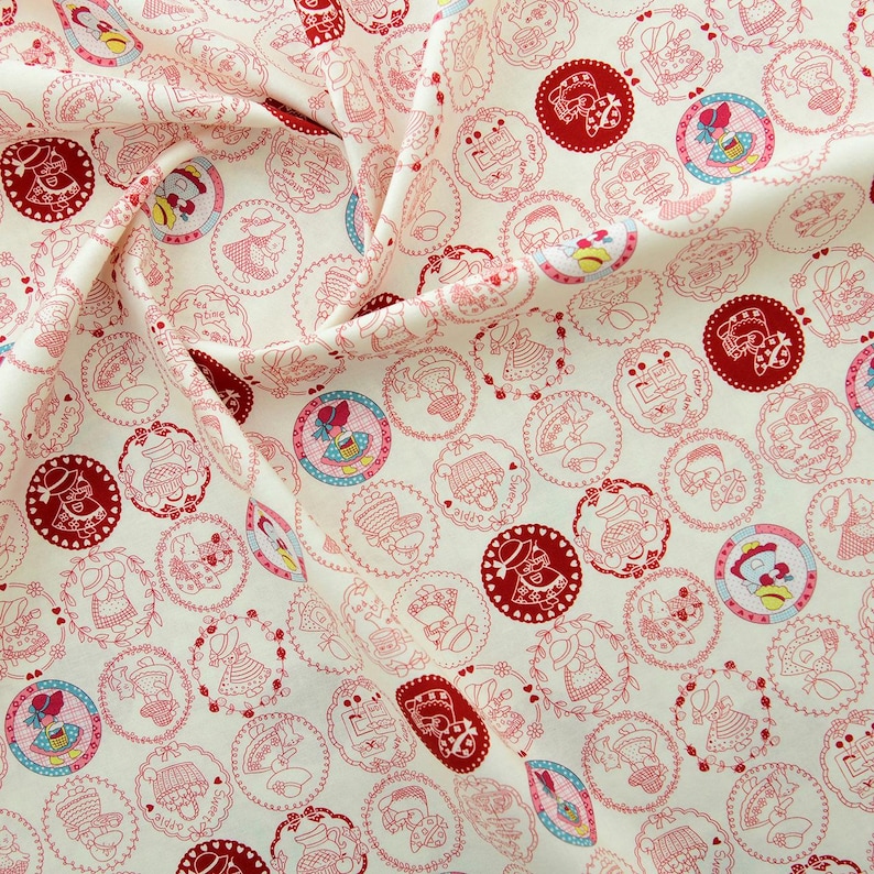 May include: White fabric with a repeating pattern of red and pink circles. Each circle contains a small illustration of a girl wearing a hat and dress. The fabric is perfect for crafting projects.
