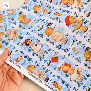 May include: A white cotton fabric with a repeating pattern of blue and white illustrations of children, blueberries, and text. The text includes the words "Blueberry Pie", "Blueberry Jam", "Blueberry Muffins", and "Easy Blueberry Scones". The fabric is 100% cotton and is handmade.