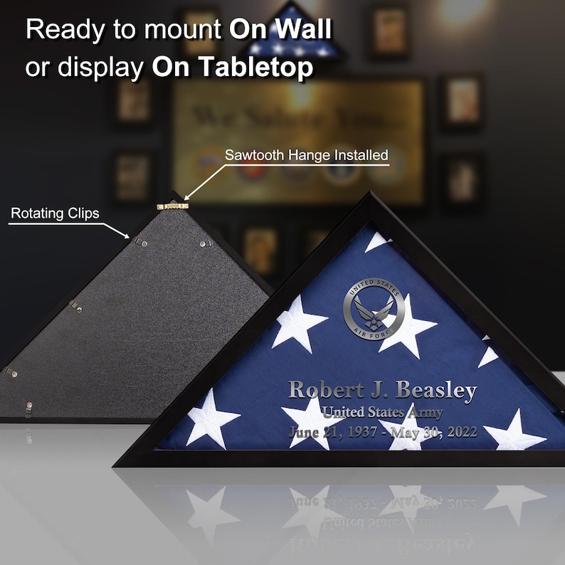 May include: A black shadow box with a folded American flag inside. The flag is displayed in a triangular shape with a silver United States Air Force emblem. The box has a sawtooth hanger installed on the back and rotating clips on the front. The text on the flag reads "Robert J. Beasley, United States Army, June 21, 1937 - May 30, 2022".