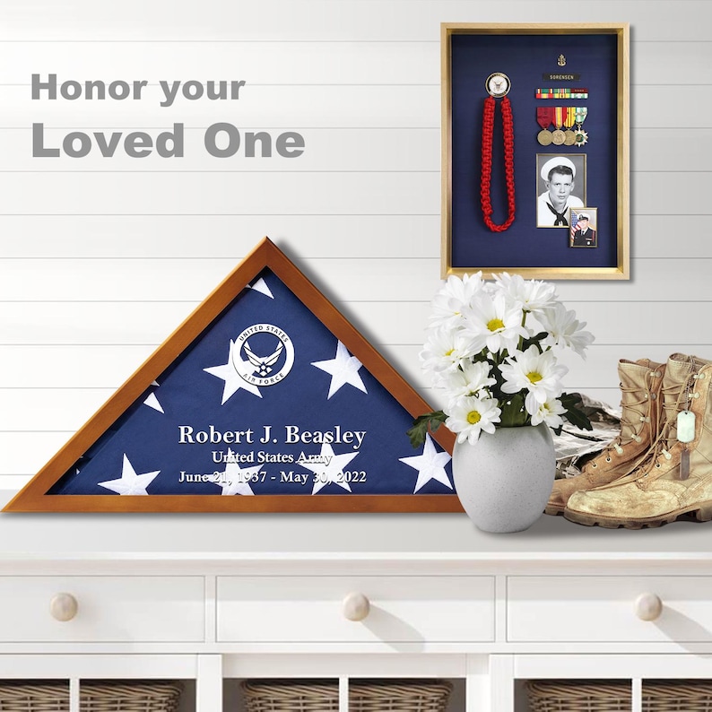 May include: A wooden shadow box with a folded American flag inside. The flag is blue with white stars and has the United States Air Force logo in the center. The box has a personalized inscription that reads "Robert J. Beasley, United States Army, June 21, 1957 - May 30, 2022".