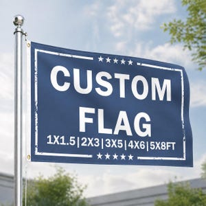 May include: A navy blue custom flag with white text and a white border, mounted on a silver pole. The flag reads "CUSTOM FLAG" with size options listed below. The sky is visible in the background.