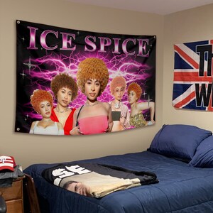 以下が含まれることがあります： 白文字で「ICE SPICE」と書かれた黒とピンクのタペストリー。タペストリーには、ピンクの稲妻を背景に、カラフルな服を着た巻き毛の女性が5人描かれている。