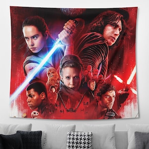 Pu&ograve; includere: Un arazzo rettangolare da parete con il design di una locandina del film Star Wars su uno sfondo rosso dominante. L'opera mostra diversi personaggi, tra cui Rey che impugna una spada laser blu brillante, Kylo Ren, Leia e Finn.