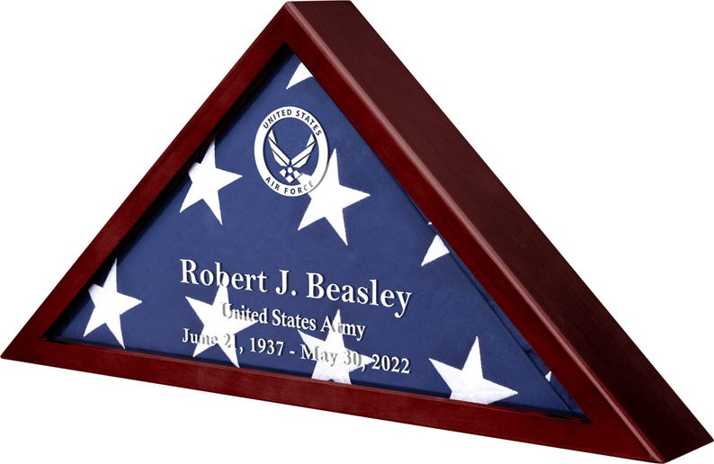 May include: A mahogany wood triangular shadow box with a folded American flag inside. The flag is blue with white stars and has the United States Air Force emblem in the upper left corner. The name "Robert J. Beasley", "United States Army", and the dates "June 21, 1937 - May 30, 2022" are engraved on the flag.