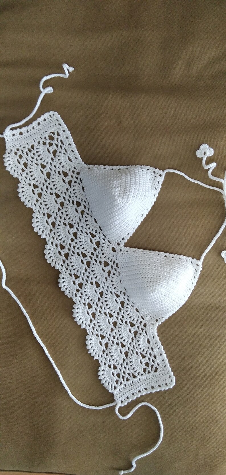 Pode incluir: Top de biqu&iacute;ni branco de croch&ecirc; com um delicado padr&atilde;o de renda. O top tem al&ccedil;as ajust&aacute;veis e um fecho de n&oacute; nas costas.