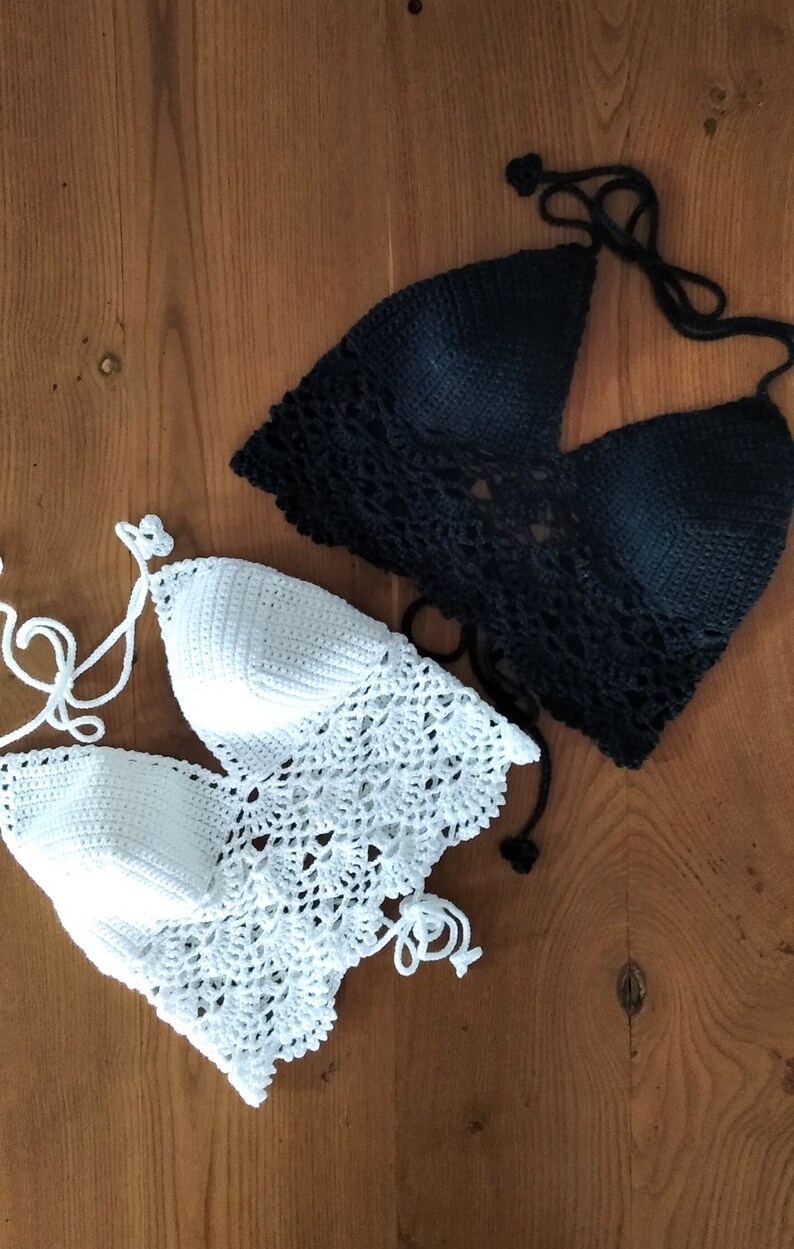 Pode incluir: Dois tops de halter de croch&ecirc;, um branco e outro preto, dispostos sobre uma superf&iacute;cie de madeira.