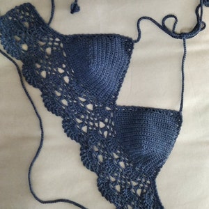 Pode incluir: Um top de biqu&iacute;ni azul de croch&ecirc; com um delicado padr&atilde;o de renda. O top tem al&ccedil;as ajust&aacute;veis e um fecho de n&oacute; nas costas.