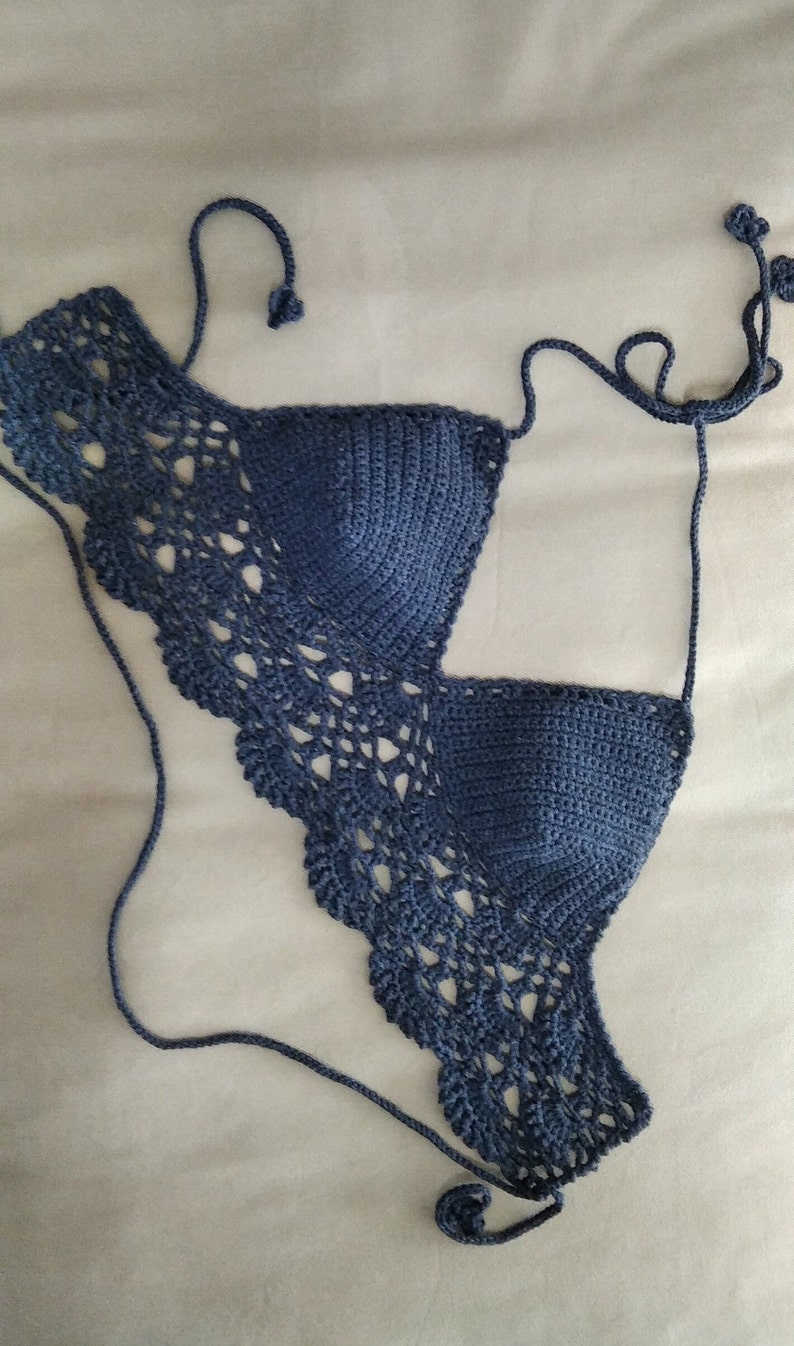 Pode incluir: Um top de biqu&iacute;ni azul de croch&ecirc; com um delicado padr&atilde;o de renda. O top tem al&ccedil;as ajust&aacute;veis e um fecho de n&oacute; nas costas.