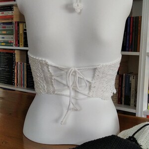 Pode incluir: Top halter branco de croch&ecirc; com costas de renda. A parte superior &eacute; amarrada nas costas com um cord&atilde;o branco.