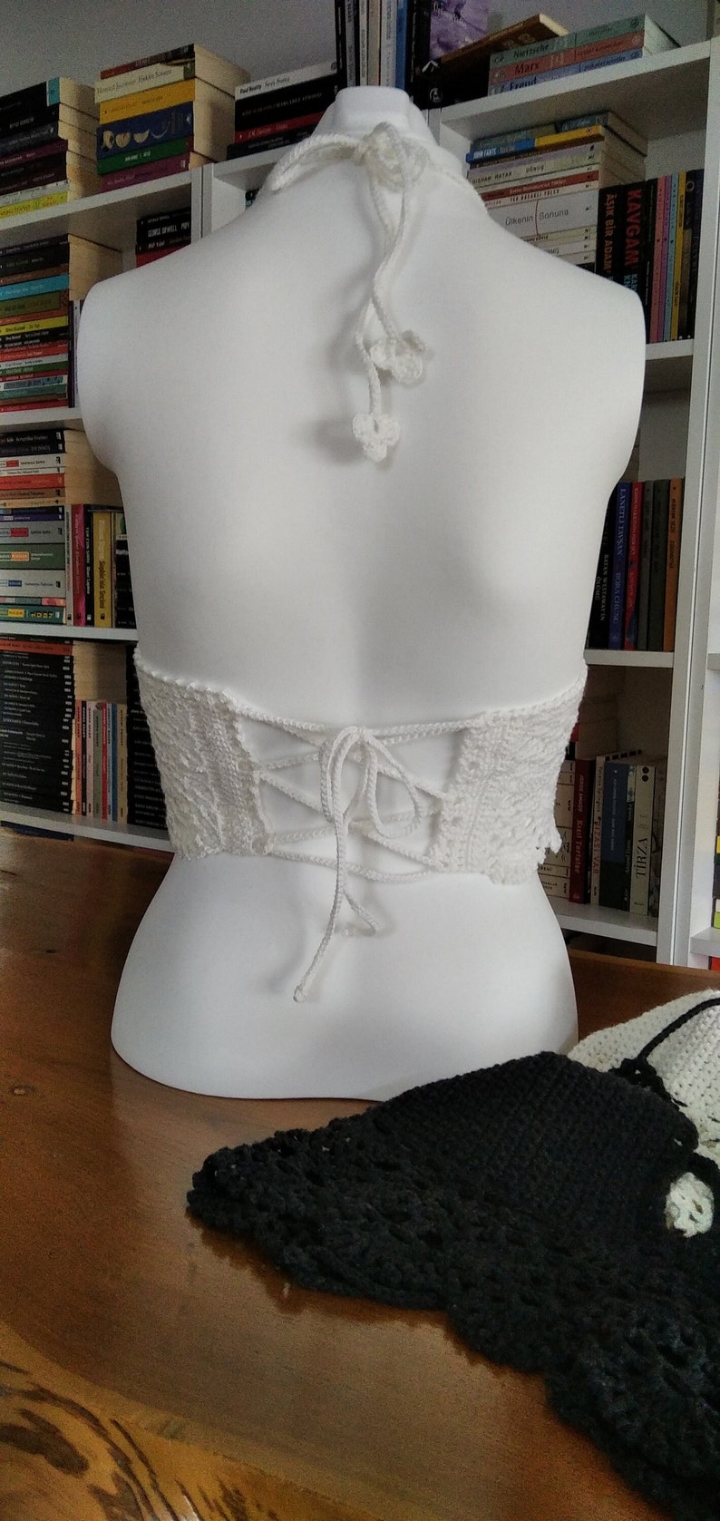 Pode incluir: Top halter branco de croch&ecirc; com costas de renda. A parte superior &eacute; amarrada nas costas com um cord&atilde;o branco.