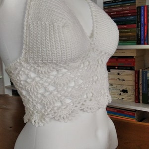 Pode incluir: Top branco de croch&ecirc; com uma delicada borda de renda. O top &eacute; exibido em um manequim branco.