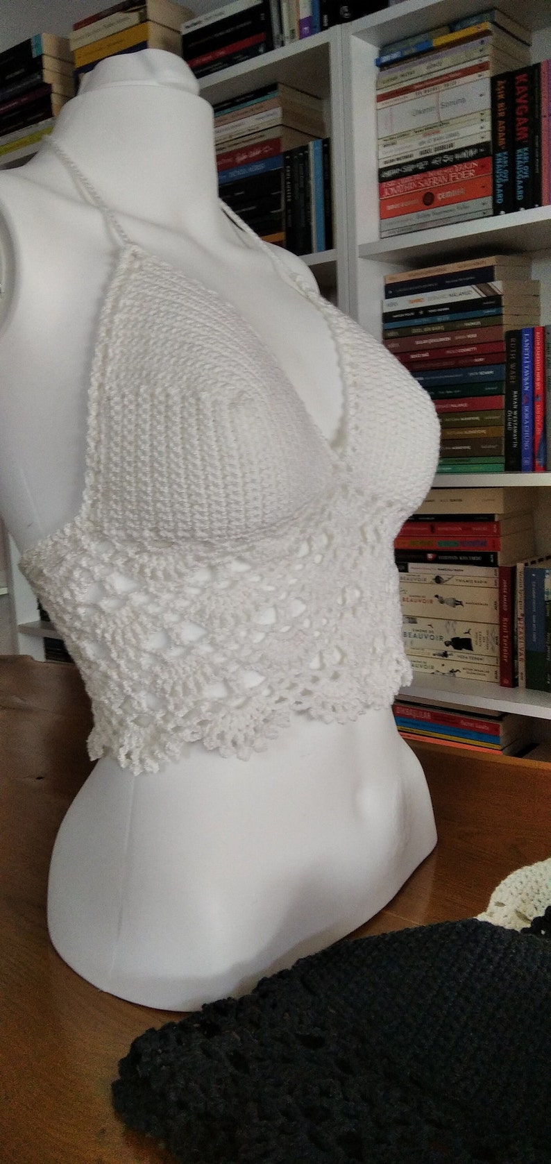 Pode incluir: Top branco de croch&ecirc; com uma delicada borda de renda. O top &eacute; exibido em um manequim branco.
