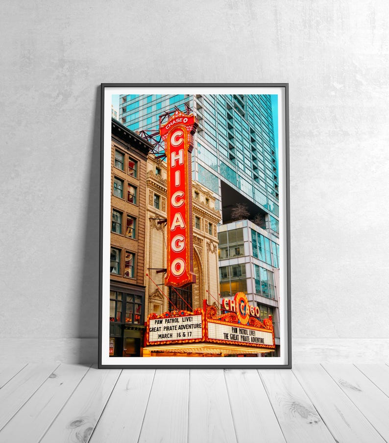 May include: A framed print of the Chicago Theatre. The iconic marquee and vertical sign with the word "CHICAGO" in red neon are prominent. The marquee advertises "PAW PATROL LIVE! GREAT PIRATE ADVENTURE MARCH 16 & 17".