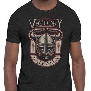 Könnte beinhalten: Ein schwarzes T-Shirt mit einem Grafikdesign eines Wikingerhelms mit Hörnern und dem Text "Sieg oder Walhalla".