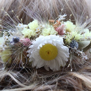 The yellow and white hair comb sitting in hair. The hair model has light brown hair with blonde highlights.