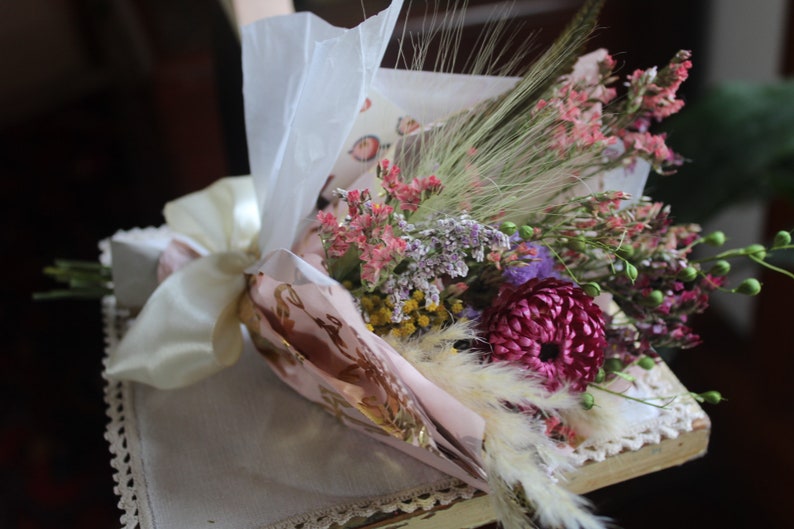 The pink and purple bouquet wrapped with pink and gold wrapping paper lying flat on a display piece.