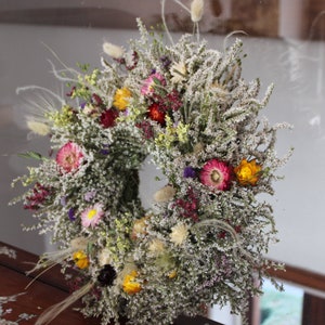 The bright straw flowers and the grasses can be seen clearly on the wreath.