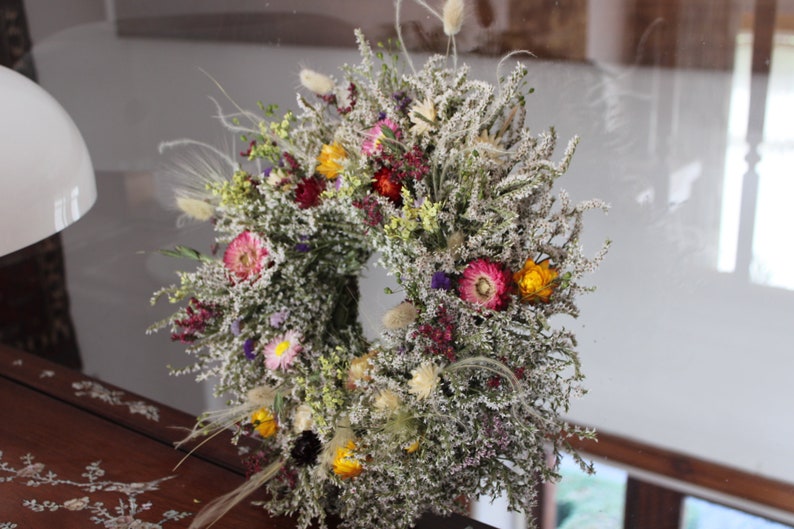 The bright straw flowers and the grasses can be seen clearly on the wreath.