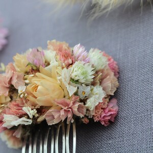 The pastel pink and peach small hair comb from the right side. The comb is sitting on a grey background.