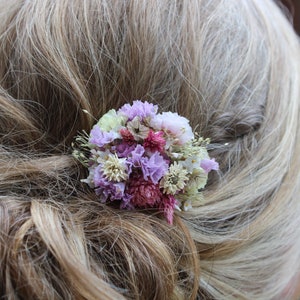 A up close photo of the small purple comb in an up do hair style. The comb is positioned on the side of the hair.