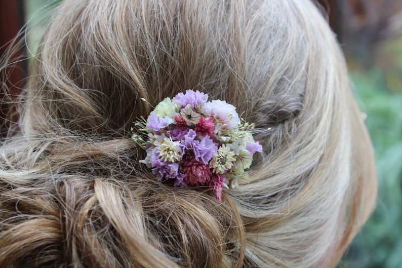A up close photo of the small purple comb in an up do hair style. The comb is positioned on the side of the hair.