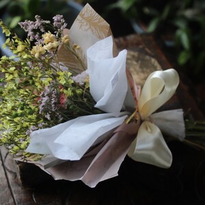 The yellow bouquet wrapped with gold and white wrapping paper lying flat on a display piece.