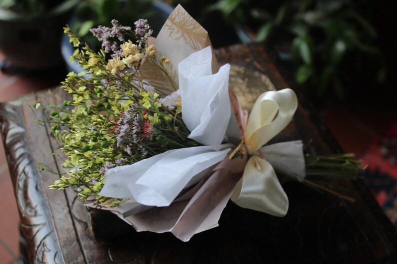 The yellow bouquet wrapped with gold and white wrapping paper lying flat on a display piece.