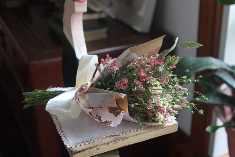 The purple and green mini bouquet wrapped in pink and gold wrapping paper.