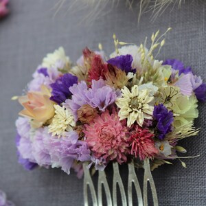 A small metal comb with purple statice, achillea the peral flowers, pink flamingo celosia, pink gomphrena, scabiosa seeds, explosion grass, silvery cream and pink straw flower.