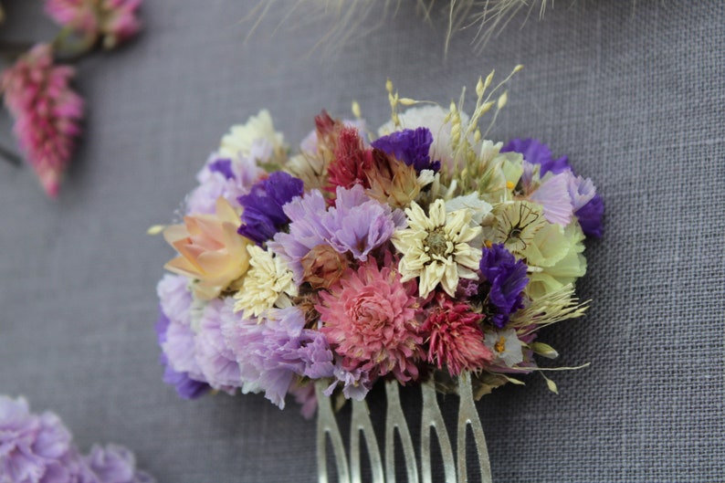 A small metal comb with purple statice, achillea the peral flowers, pink flamingo celosia, pink gomphrena, scabiosa seeds, explosion grass, silvery cream and pink straw flower.