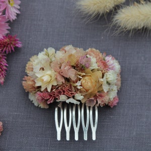 The pastel pink and peach small hair comb on the grey background.