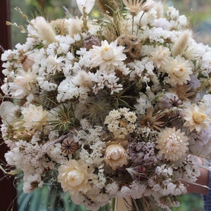 The white bouquet being held in a hand. The details of the flowers shape are more obvious in this photo.