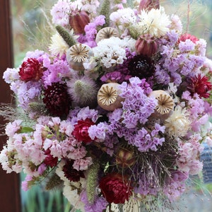 The purple bouquet being held in a hand. The details of the flowers shape are more obvious in this photo.