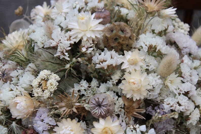 The white bridesmaid bouquet. The dried flowers res white straw flower, white achillea, poppy seed heads, scabiosa seed heads, white statice and nigella seed pods.