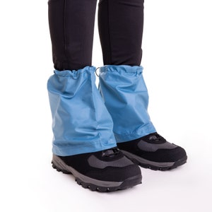 May include: A pair of blue gaiters worn over black hiking boots. The gaiters are made of a water-resistant material and have a drawstring closure at the top.