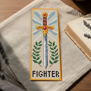 May include: Cross-stitched bookmark featuring a sword design with a gold hilt and red accents, set against a blue and white background. Green laurel branches flank the sword. The word "FIGHTER" is stitched at the bottom in capital letters.