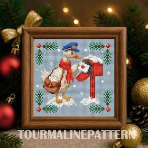 Op de afbeelding: Kruissteekkunstwerk in een houten lijst. De afbeelding toont een gans met een blauwe hoed en rode sjaal, die post bezorgt aan een rode brievenbus in een besneeuwde scène. De tekst "TOURMALINEPATTERN" staat onderaan.