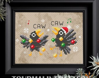 May include: Cross-stitch pattern featuring two black birds with Christmas lights and the text "CAW CAW".