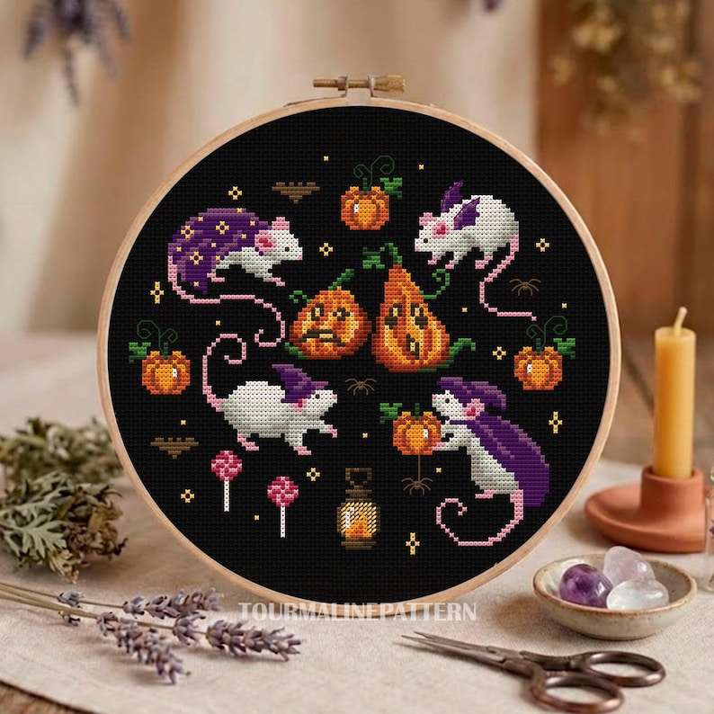 A cross-stitch design featuring white mice with purple capes interacting with pumpkins and other Halloween elements. The background is black, emphasizing the bright colors of the mice and pumpkins.