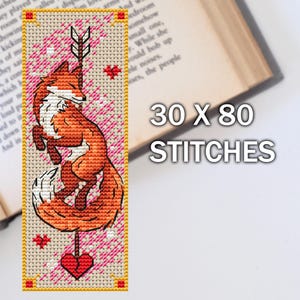Bookish cross stitch narrow bookmark design showing an orange fox with arrow on beige fabric, next to open book, TourmalinePattern on Etsy.