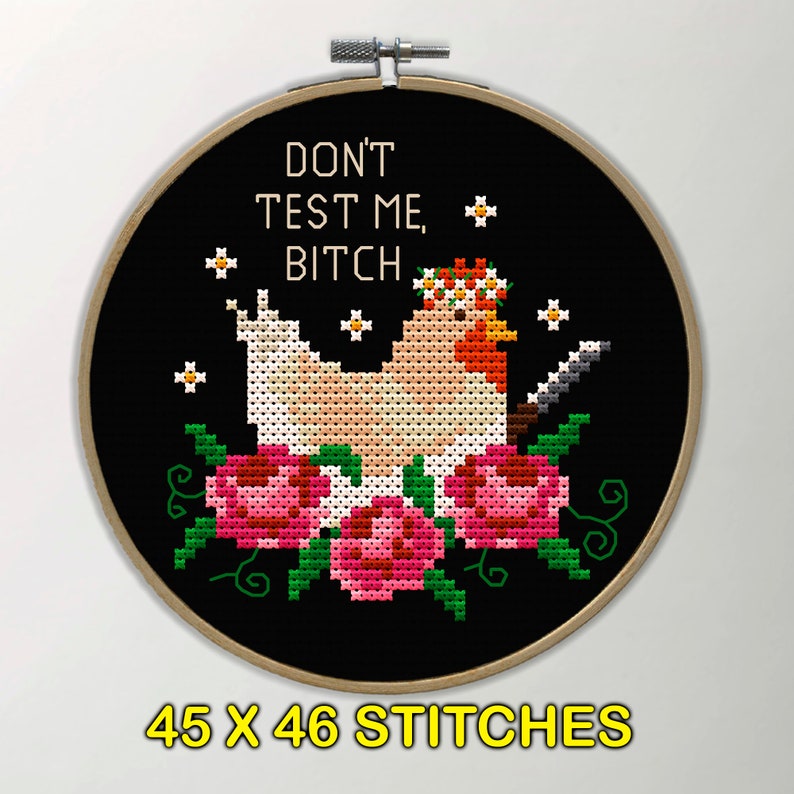 Puede incluir: Bordado de punto de cruz en un aro de madera. El dise&ntilde;o presenta una gallina con un cuchillo, una corona floral y el texto "DON'T TEST ME, BITCH." La pieza tiene 45 x 46 puntadas.