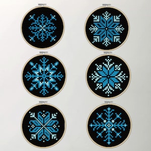 May include: Six embroidery hoops with black fabric and blue and white snowflake designs.