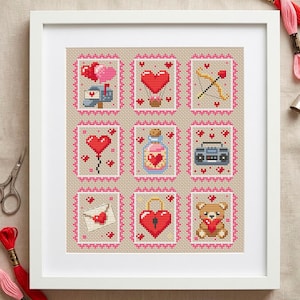 Può includere: Arte a punto croce incorniciato con nove disegni a forma di francobollo a tema San Valentino. Ogni quadrato con bordo rosa raffigura cuori, una cassetta delle lettere, un arco e una freccia, un palloncino, una bottiglia, un boombox, una busta, un lucchetto e un orsacchiotto.