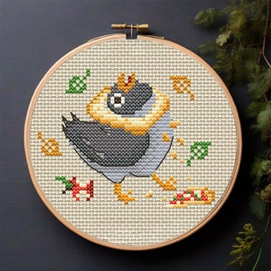 Puede incluir: Patrón de punto de cruz de un pájaro de dibujos animados con una corona y una corona de flores amarilla, sosteniendo una rebanada de pizza. El pájaro está rodeado de hojas verdes y coronas amarillas.