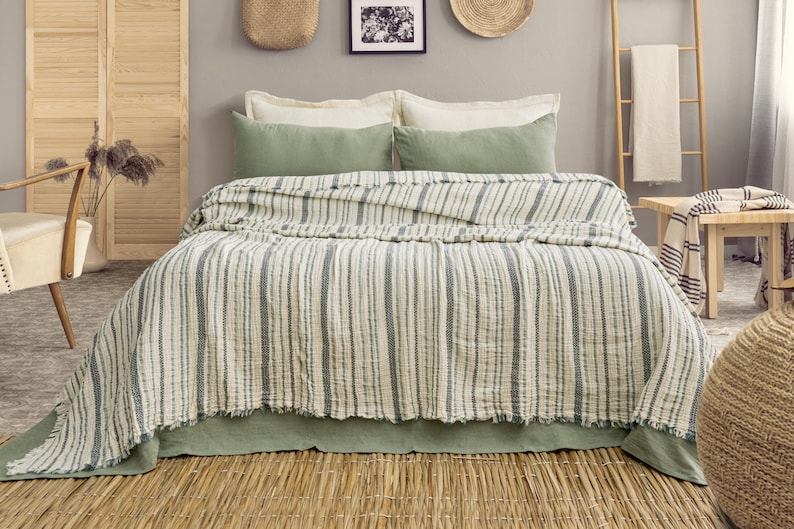 Pu&ograve; includere: Un letto con una trapunta a righe bianche e grigie, completata da cuscini verdi e un copriletto verde. La stanza presenta una scala di legno, un tavolino di legno e decorazioni murali, creando un ambiente camera da letto accogliente.