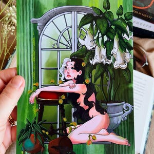 May include: A rectangular art print featuring a stylised illustration of a person with long black and white hair kneeling before a large arched window. The scene includes a potted plant with white trumpet-shaped flowers and several small Venus flytraps.