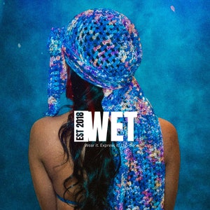 May include: A person wearing a blue and purple crocheted hat with the text "WET EST 2018" and the words "Wear it. Express it. Top-tier."