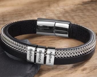 May include: Black leather bracelet with a silver chain detail and three silver charms engraved with the names "Baldwin", "Belinda", and "Nathan".