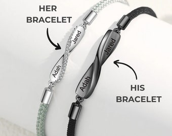 May include: Two infinity symbol bracelets with the names "Jared" and "Adah" engraved on them. The bracelets are made of black and silver cord and have a black and silver infinity symbol charm.